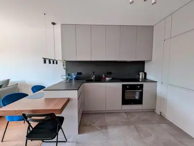 a kitchen with white cabinets and a wooden table at Riverside Base Zabłocie in Kraków