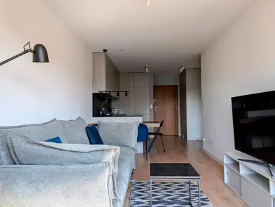 a living room with a couch and a kitchen at Riverside Base Zabłocie in Kraków