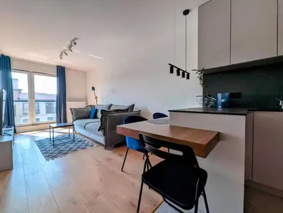 a kitchen and living room with a table and a couch at Riverside Base Zabłocie in Kraków