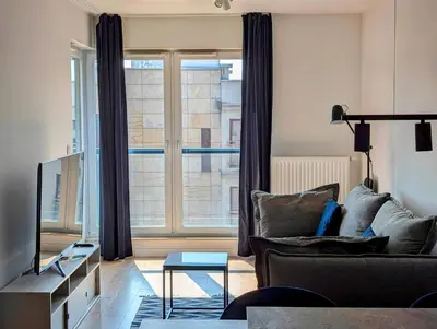a living room with a couch and a large window at Riverside Base Zabłocie in Kraków