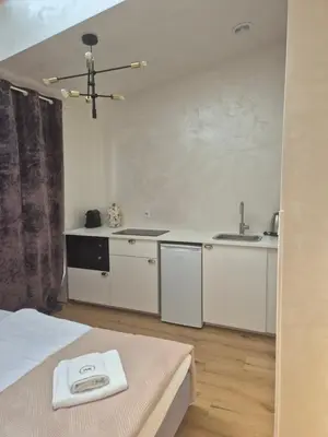 a white kitchen with a sink and a bed in a room at Aparthotel Miodowa 25 in Kraków