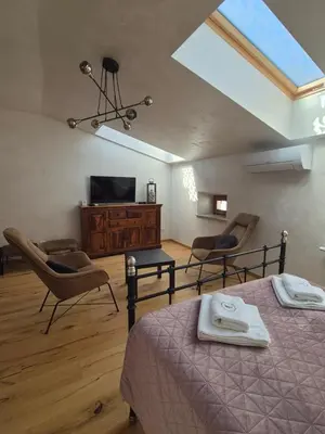 a bedroom with a bed and two chairs and a television at Aparthotel Miodowa 25 in Kraków