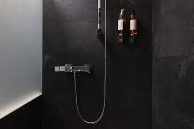 a black bathroom with a shower with a hose at Aparthotel Miodowa 25 in Kraków