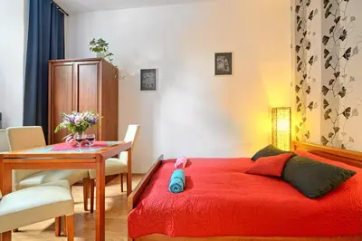 a bedroom with a red bed and a wooden table at City Fever Apartment Kazimierz, WiFi in Kraków