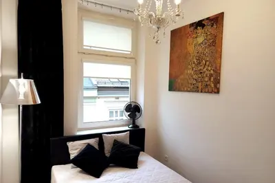 a bedroom with a bed with a chandelier and a window at Old Town - Traugutta Street flat 9 in Kraków