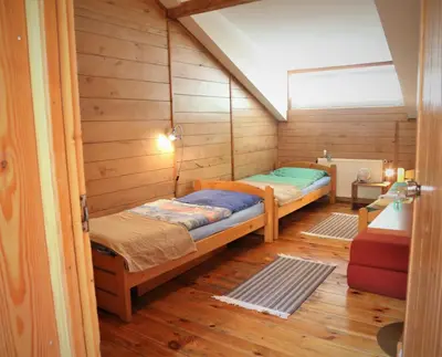 a bedroom with two beds in a room with wooden walls at Gospodarstwo Agroturystyczne Stary Młyn Wilczkowice in Michałowice