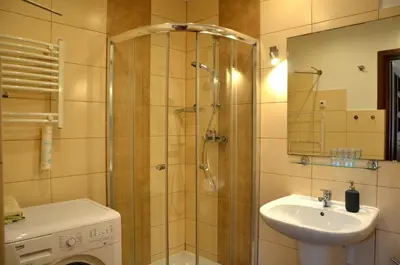 a bathroom with a shower and a sink and a washing machine at Caffe Latte, City Center Apartment in Kraków