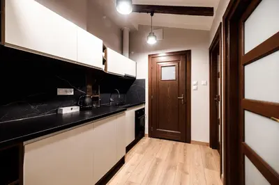 a kitchen with white cabinets and a black counter top at Air-conditioned attic apartment Old Town Main Railway Station in Kraków