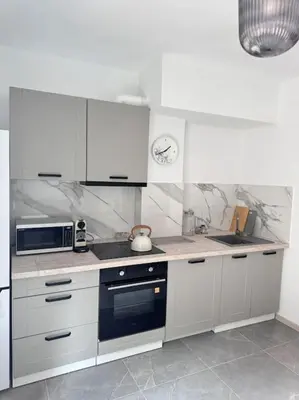 a kitchen with white cabinets and a stove top oven at Apartamenty na Wodzienowskiego in Kraków