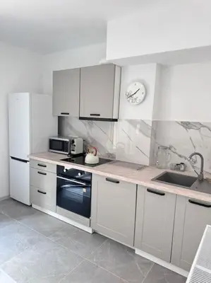 a kitchen with white cabinets and a clock on the wall at Apartamenty na Wodzienowskiego in Kraków