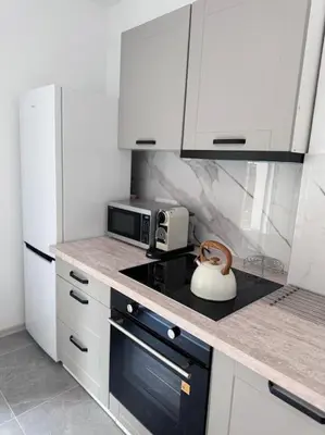 a kitchen with white cabinets and a tea kettle on the stove at Apartamenty na Wodzienowskiego in Kraków