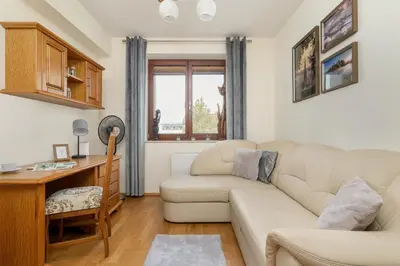 a living room with a couch and a desk at Przytulny Apartament z Klimatyzacją i Parkingiem by Noclegi Renters in Kraków
