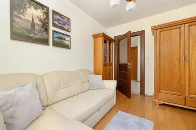 a living room with a white couch and wooden floors at Przytulny Apartament z Klimatyzacją i Parkingiem by Noclegi Renters in Kraków