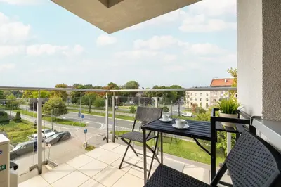 a balcony with a table and chairs and a view of a street at Przytulny Apartament z Klimatyzacją i Parkingiem by Noclegi Renters in Kraków