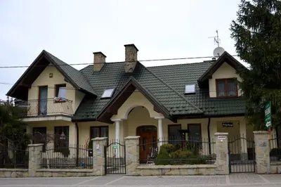 a garden in front of a house with trees and bushes at Pensjonat Pod Długą Polaną in Nowy Targ