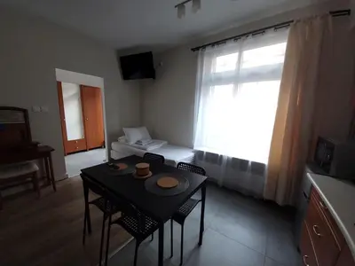 a living room with a table and chairs and a window at KĄCIK Apartament in Kraków