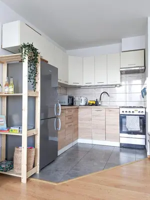 a kitchen with white cabinets and a stainless steel refrigerator at Apartament Jabłko-Mięta w Tymbarku in Tymbark
