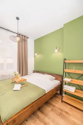 a bedroom with a large bed with green walls at Kraków Główny Apt - Top Location, Park&Tram nearby - by Rentujemy in Kraków