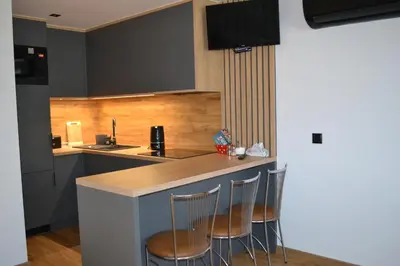a kitchen with three bar stools at a counter at Domek na Dogalu in Filipowice