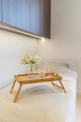 a wooden table with two glasses and flowers on a bed at Kraków Prestige Suites - 61m2, Parking, Balcony, Workspace, AC - by Rentujemy in Kraków