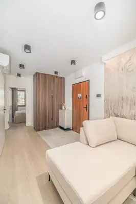 a living room with a white couch and wooden cabinets at Kraków Prestige Suites - 61m2, Parking, Balcony, Workspace, AC - by Rentujemy in Kraków