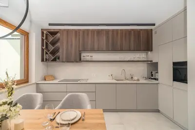 a kitchen with white cabinets and a wooden table at Kraków Prestige Suites - 61m2, Parking, Balcony, Workspace, AC - by Rentujemy in Kraków