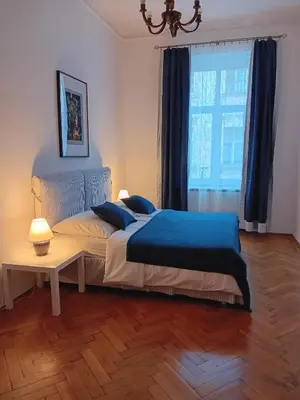a bedroom with a bed with blue sheets and a window at Apartament Róży in Kraków