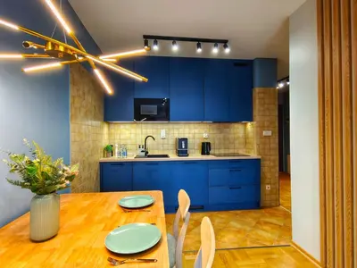 a kitchen with blue cabinets and a wooden table at Bronowicka Comfort Apartment in Kraków