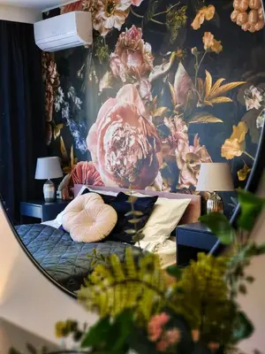 a bedroom with a floral wallpaper with a bed and two lamps at Bronowicka Comfort Apartment in Kraków