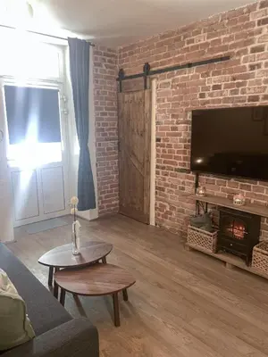 a living room with a brick wall and a fireplace at Cracovia Kazimierz Historic Heart Accessible Apartament in Kraków