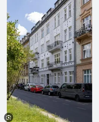 a large white building with cars parked on a street at Cracovia Kazimierz Historic Heart Accessible Apartament in Kraków