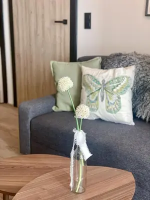 a vase with flowers on a table in front of a couch at Cracovia Kazimierz Historic Heart Accessible Apartament in Kraków