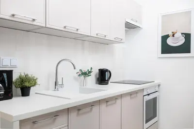 a kitchen with white cabinets and a sink at Retro Glamour with a Modern Edge - by Upstairs in Kraków