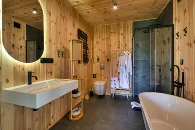 a bathroom with a tub and a large mirror at Black Deer - z Sauną na Tarasie, Jacuzzi i Widokiem na Góry - by Deer Hills Luxury Apartments in Kocoń