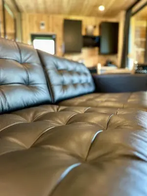 a brown leather couch sitting in a living room at Black Deer - z Sauną na Tarasie, Jacuzzi i Widokiem na Góry - by Deer Hills Luxury Apartments in Kocoń