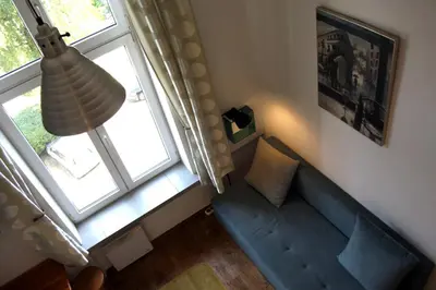 a living room with a blue couch and a window at Smallest Spot in Town, City Center in Kraków