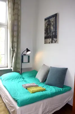 a bed with green sheets and a lamp in a room at Smallest Spot in Town, City Center in Kraków
