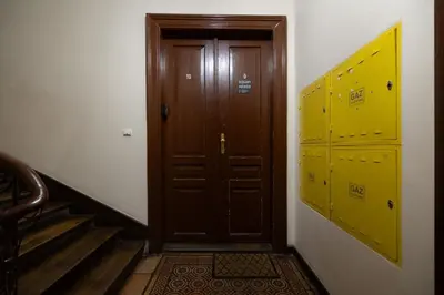 a hallway with a wooden door and stairs with yellow lockers at 1-bedroom Apartment - Radziwiłłowska 14 Street in Kraków
