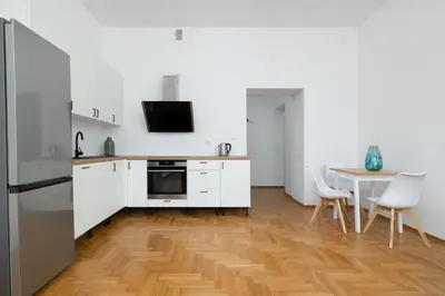 a kitchen with white cabinets and a table with chairs at 1-bedroom Apartment - Radziwiłłowska 14 Street in Kraków