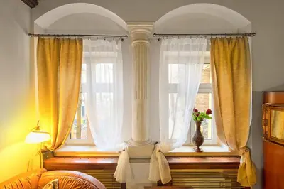 a bedroom with two windows with a vase of flowers on the window sill at Knights&Lords Apartment, Old Town in Kraków