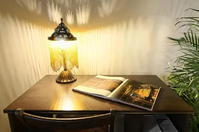 a table with a lamp and a book and a christmas tree at Knights&Lords Apartment, Old Town in Kraków