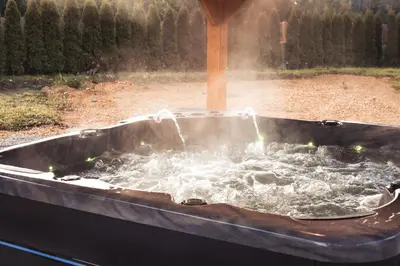 a hot tub filled with water in a garden at Beskidia - Noclegi w Beskidach in Roczyny