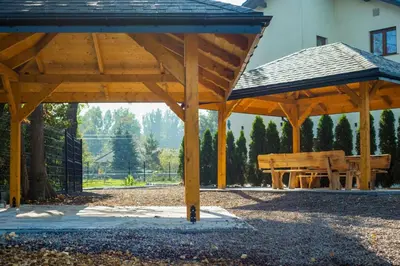 a wooden pavilion with two benches in a park at Beskidia - Noclegi w Beskidach in Roczyny