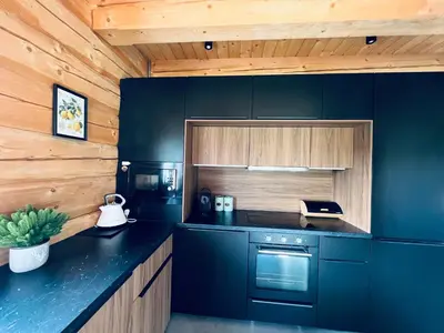 a kitchen with black counters and wooden walls at Kowalowa Chata Zawoja in Zawoja