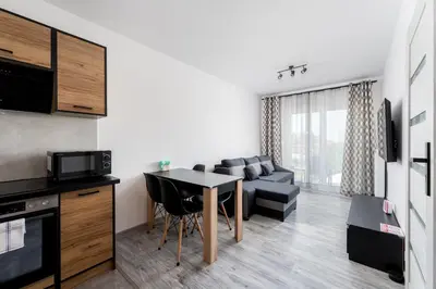 a kitchen and living room with a table and a couch at Gusta Cosy Apartment by BookingHost in Kraków