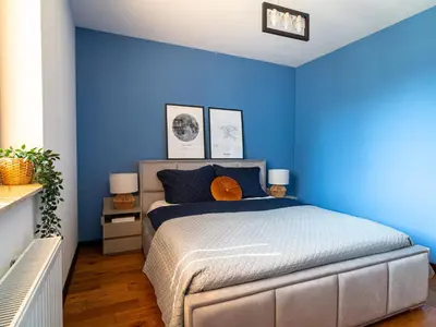 a bedroom with blue walls and a bed at Grey Wall Apartment Kraków in Kraków