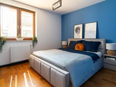 a bedroom with blue walls and a bed at Grey Wall Apartment Kraków in Kraków