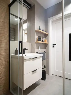 a bathroom with a sink and a glass shower at Grey Wall Apartment Kraków in Kraków