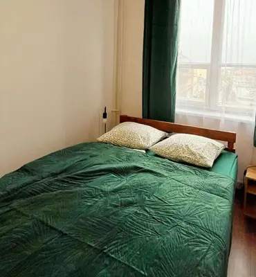 a bedroom with a green bed with a window at TomTom Hostel in Kraków