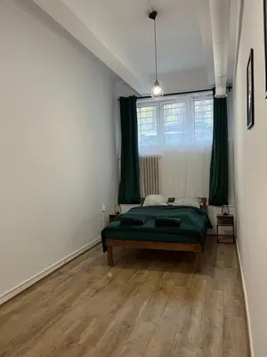 a bedroom with a green bed and a window at TomTom Hostel in Kraków